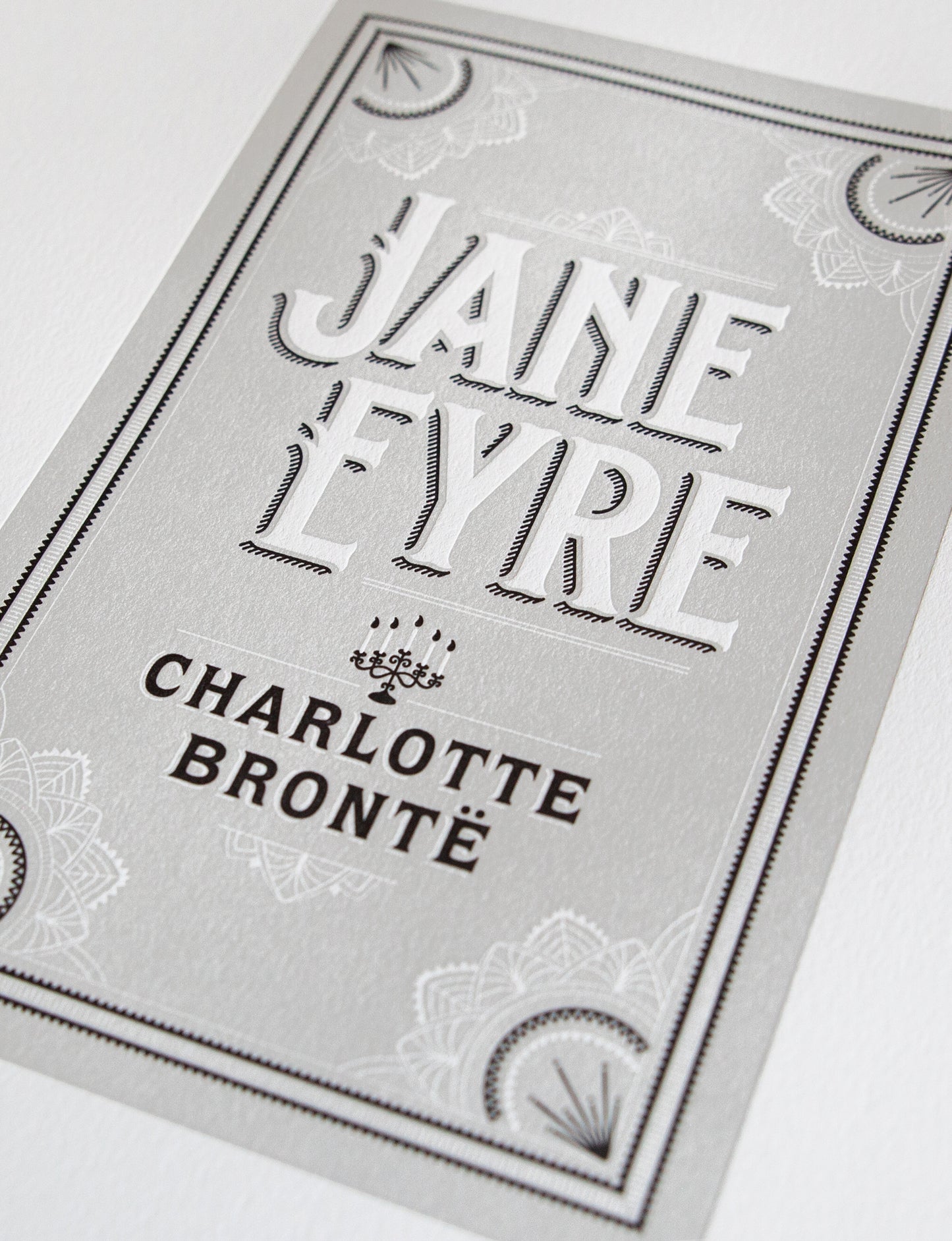 Close-up of a 2-color letterpress print in gray and black. Printed artwork is an illustrated book cover of Jane Eyre including custom hand lettering.