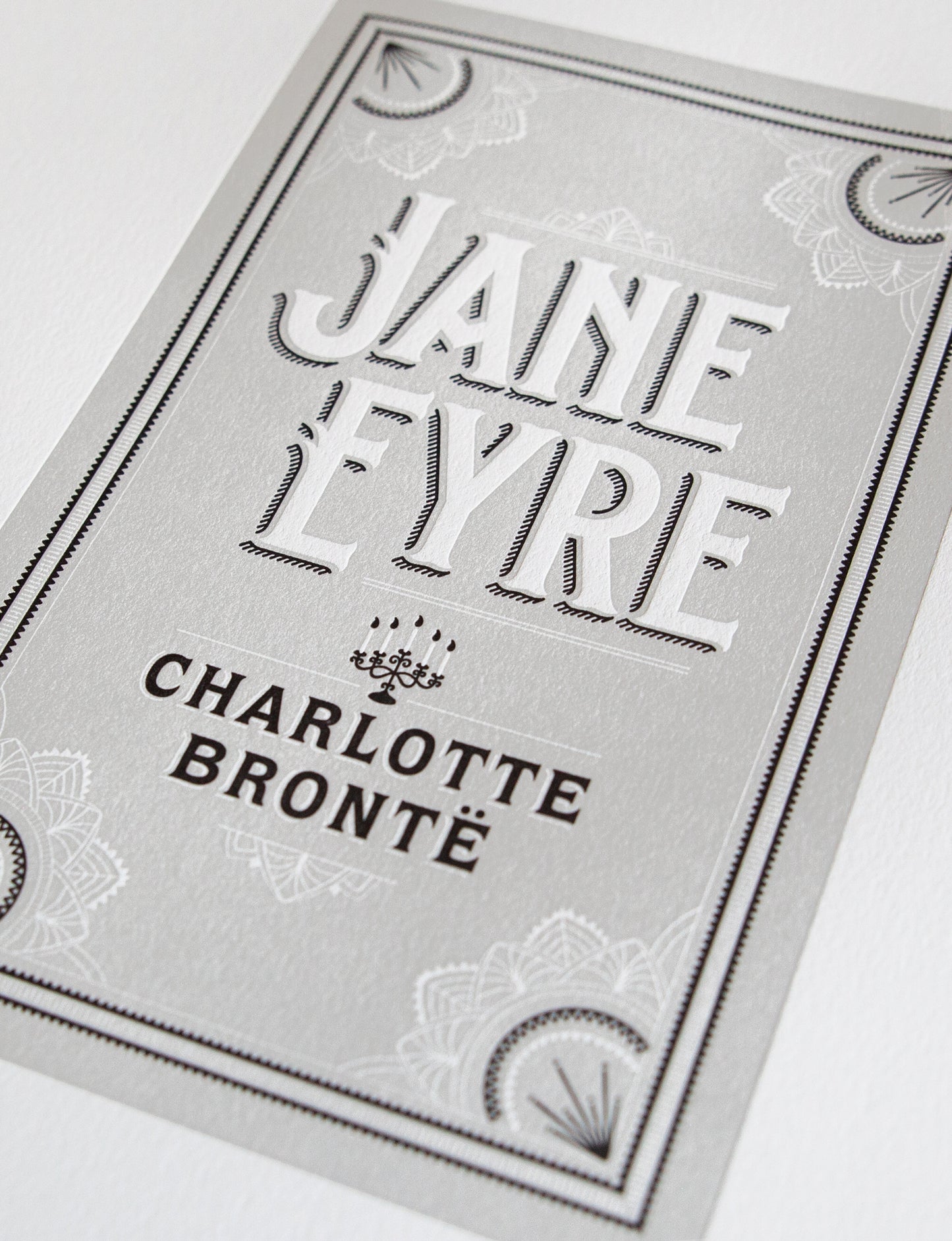 Close-up of a 2-color letterpress print in gray and black. Printed artwork is an illustrated book cover of Jane Eyre including custom hand lettering.