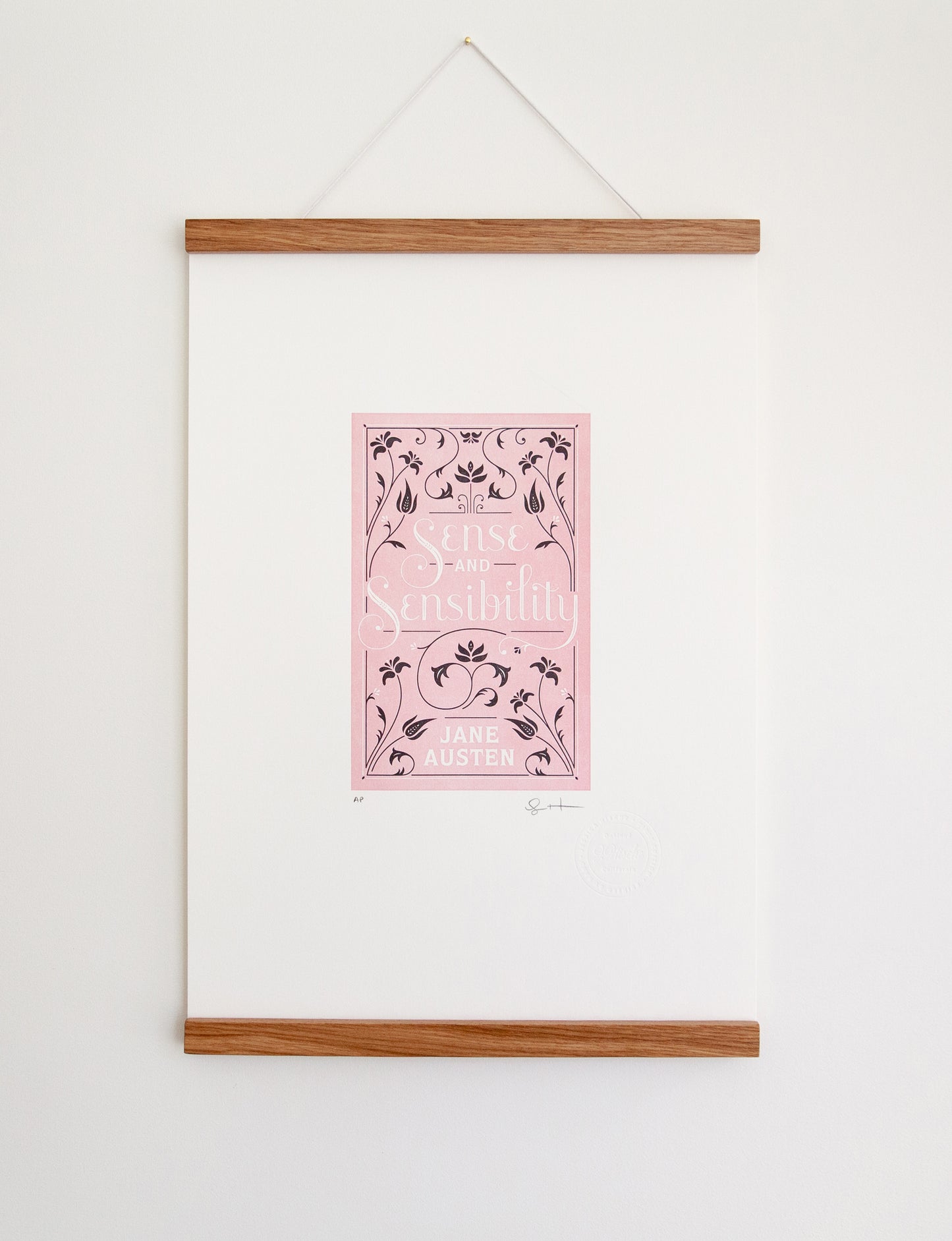 Framed 2-color letterpress print in pink and black. Printed artwork is an illustrated book cover of Sense and Sensibility including custom hand lettering.