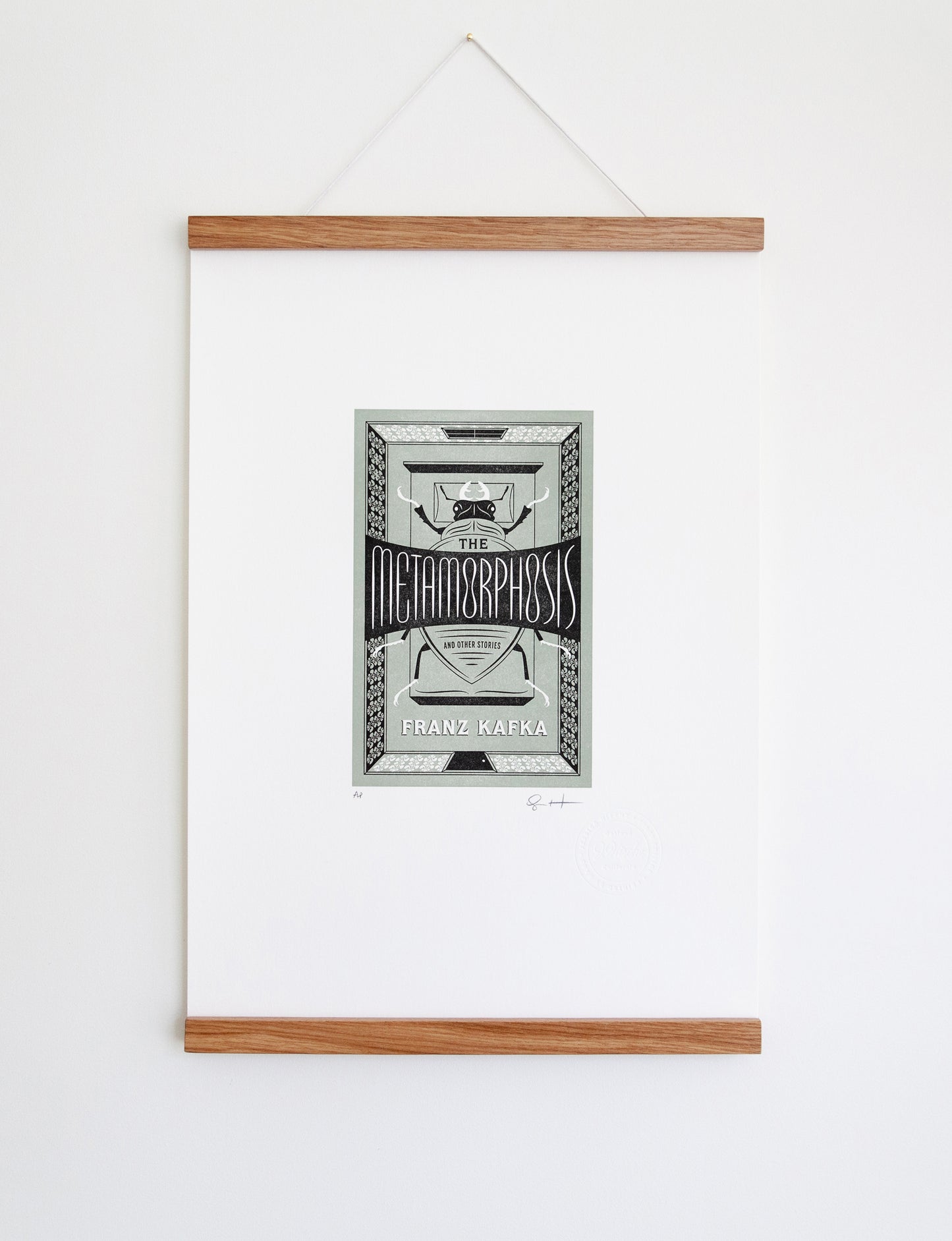Framed 2-color letterpress print in green and black. Printed artwork is an illustrated book cover of The Metamorphosis including custom hand lettering.
