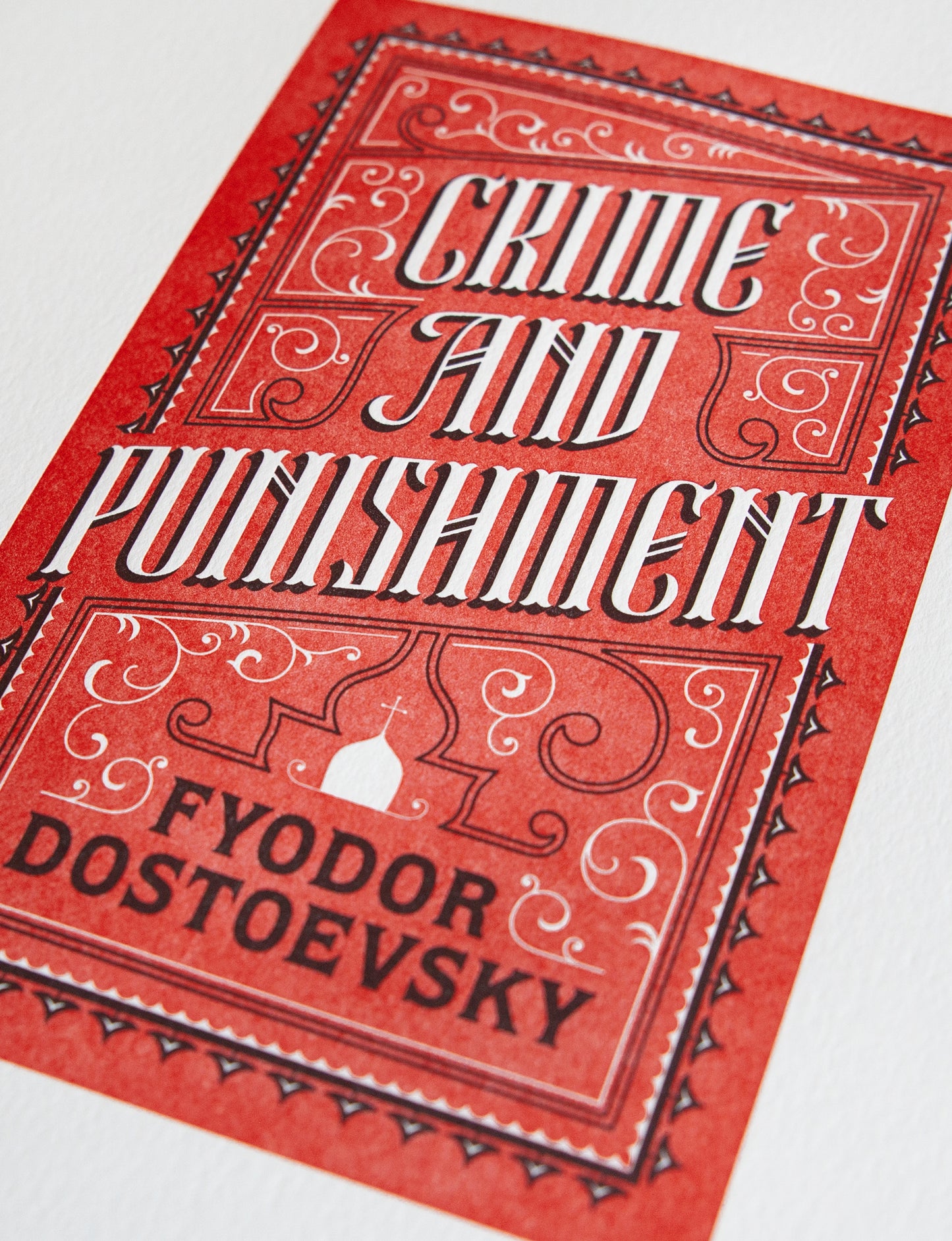 Close-up of a 2-color letterpress print in red and black. Printed artwork is an illustrated book cover of Crime and Punishment including custom hand lettering.