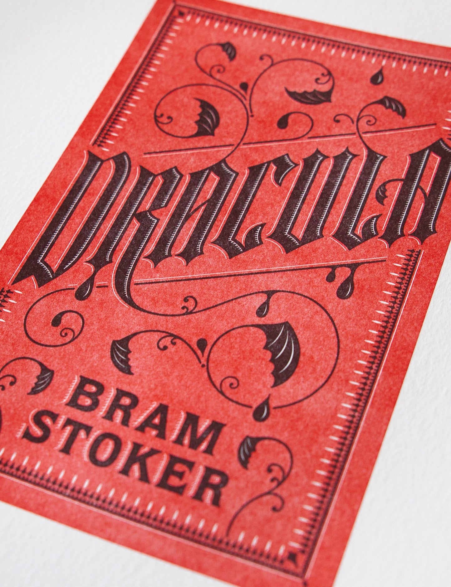 Close-up of a 2-color letterpress print in red and black. Printed artwork is an illustrated book cover of Dracula including custom hand lettering.