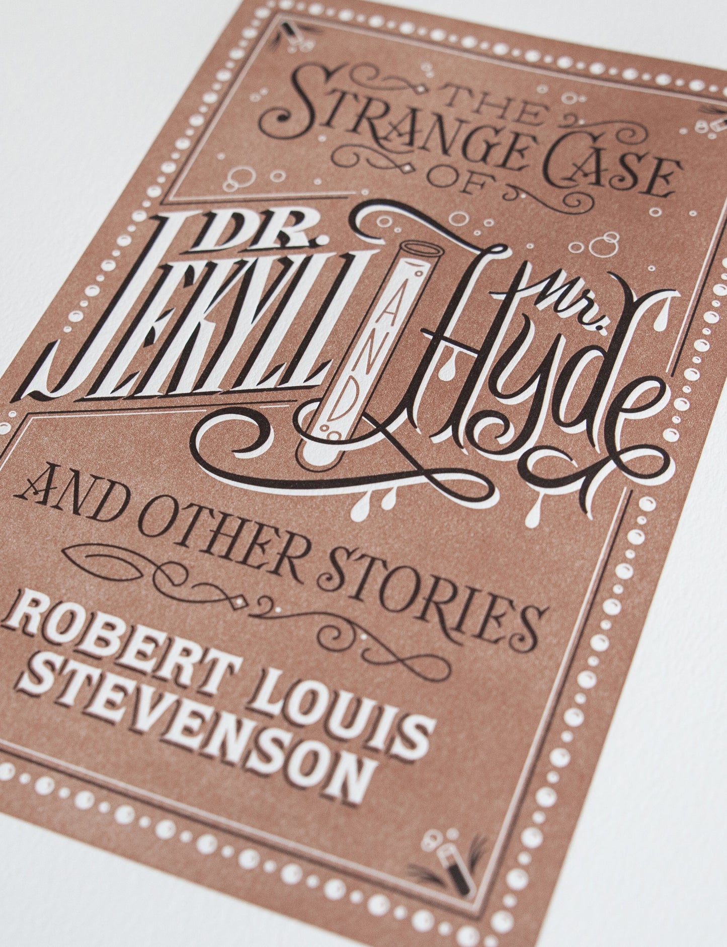 Close-up of a 2-color letterpress print in brown and black. Printed artwork is an illustrated book cover of Dr. Jekyll and Mr. Hyde including custom hand lettering.