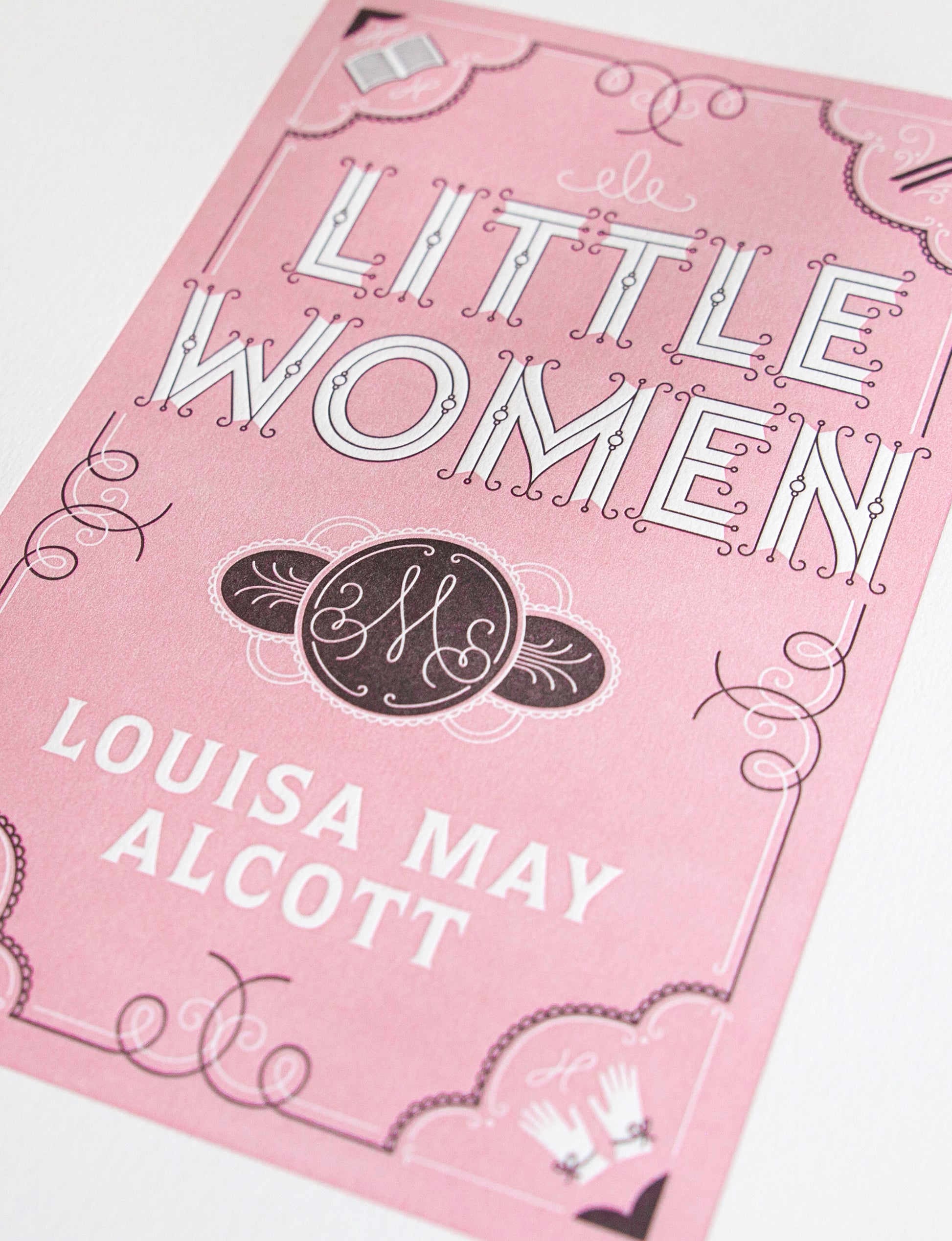 Close-up of a 2-color letterpress print in pink and black. Printed artwork is an illustrated book cover of Little Women including custom hand lettering.