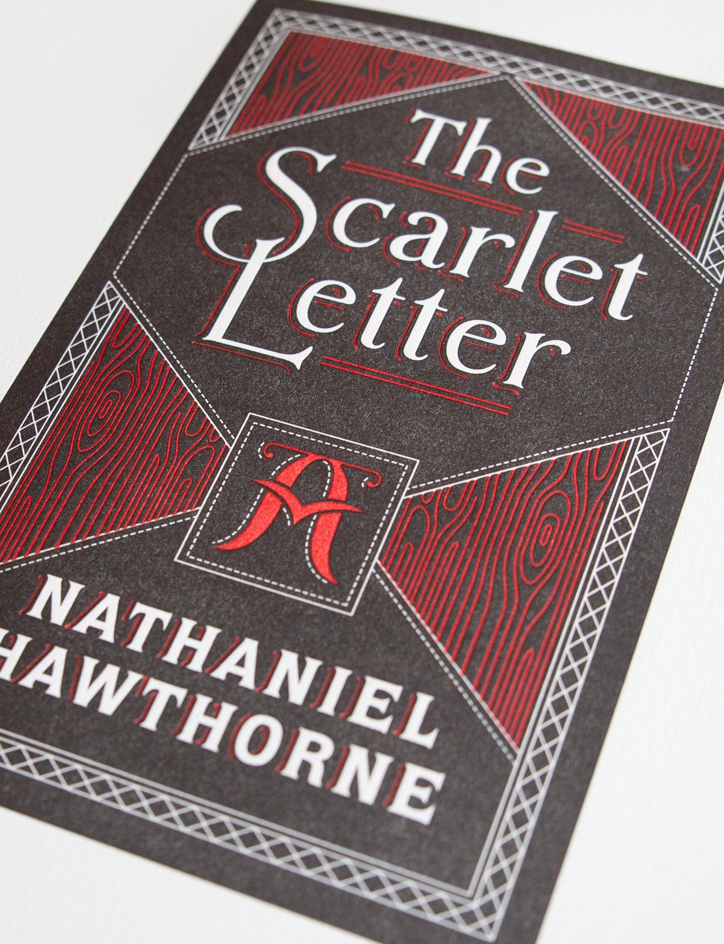 Close-up of a 2-color letterpress print in black and red. Printed artwork is an illustrated book cover of The Scarlet Letter including custom hand lettering.