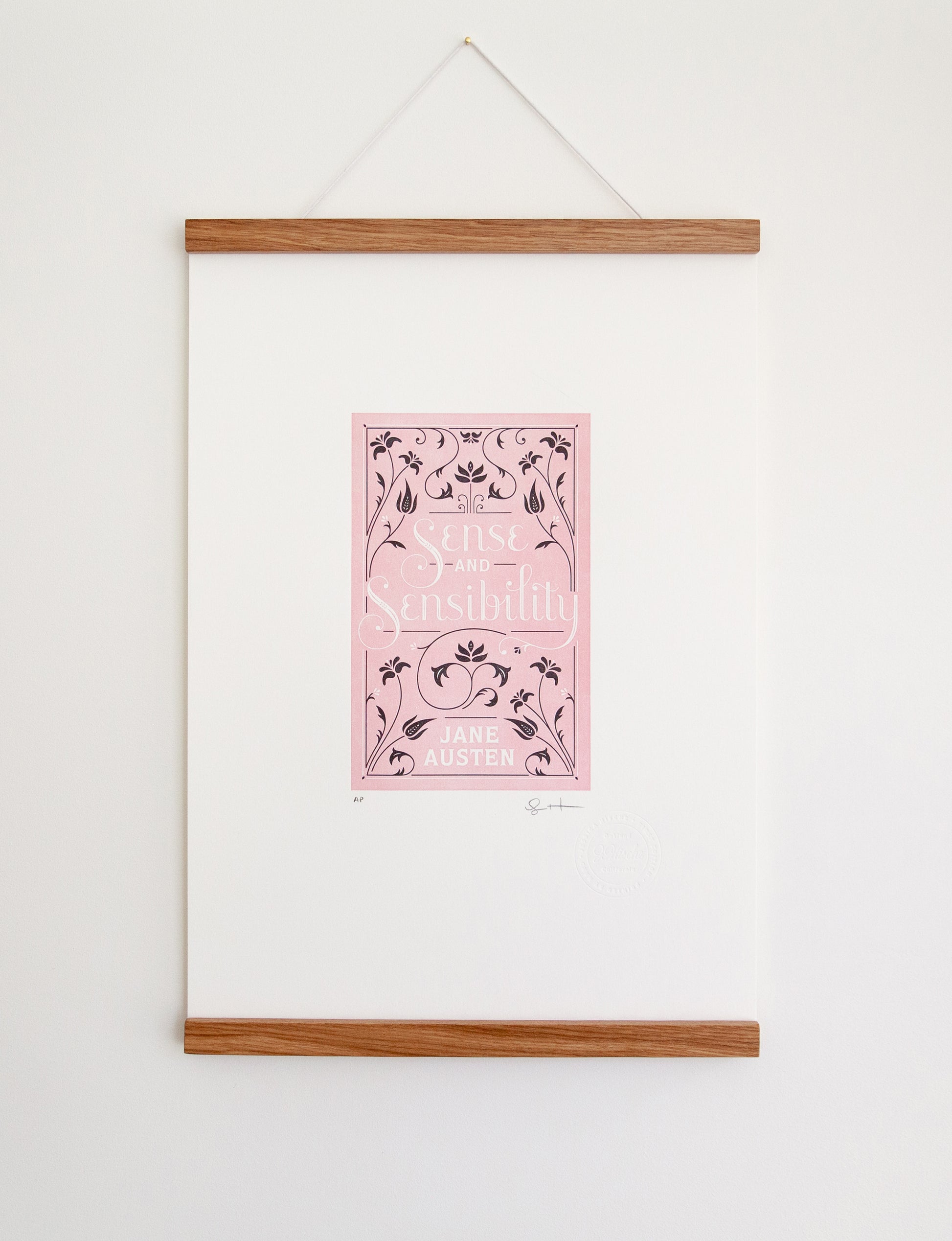 Framed 2-color letterpress print in pink and black. Printed artwork is an illustrated book cover of Sense and Sensibility including custom hand lettering.